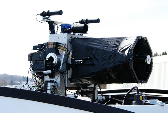 The ground-based telescope, with cameras and laser light sources for automatic precision positioning. To reduce the level of stray light, the normally open structure was lined with black fabric.